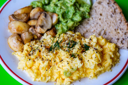London UK June 25 2025,  Scambled Eggs With Mashed Avacado Fried Musherooms and Seeded Breadの写真素材