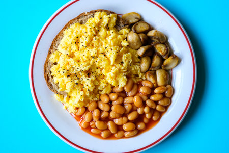 London UK June 25 2025,  Scrambled Eggs Fried Mushrooms Baked Beans and Tomato Sauce