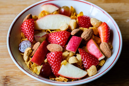 London UK, June 20 2025, Bowl Of Corn Flakes Breakfast Cereal With Fresh Fruit And Mixed Nuts