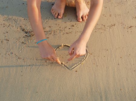 drawing hearts in a sandの写真素材