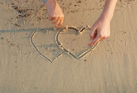 drawing hearts in a sandの写真素材
