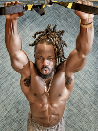 Handsome, young, muscular African American man, a bodybuilder, exercising in the gym.の写真素材