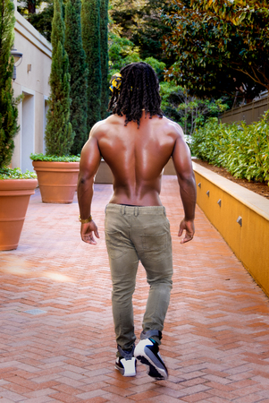 Young muscular shirtless African American man walking showing his back.の写真素材