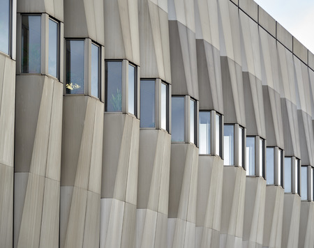 Facade of a modern building made of concrete with small windows in cloudy weather