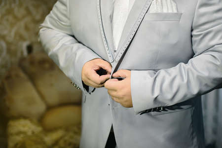 a man buttons up a gray jacket in a retro styleの写真素材