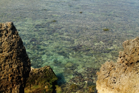 The rocks submerged in sea water by the beach with clear waterの写真素材