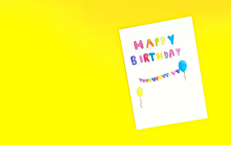 Happy birthday card kid handwriting on yellow background. Children or baby draw and paint colorful text with imagine on white paper. For fill text on mock-up or poster. Top view.
