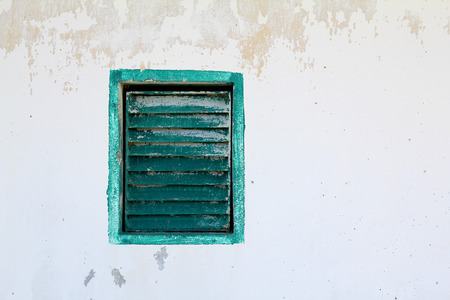 green window with shutter on old white wall