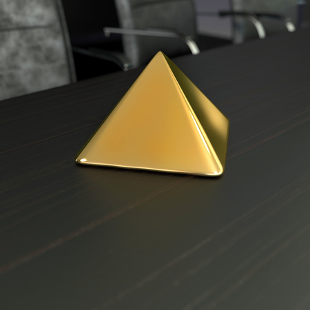 simple golden pyramide on the table in office roomの写真素材