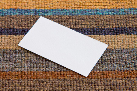 blank white paper card with rough texture on textile backgroundの写真素材