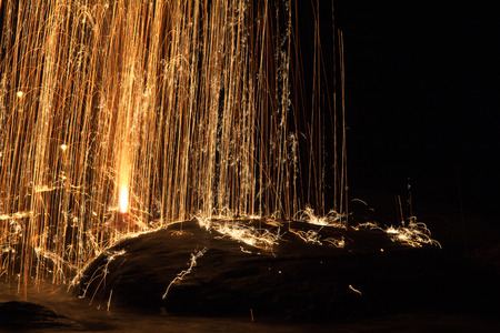 bright yellow festive fire works with sparks falling down on stones and into water