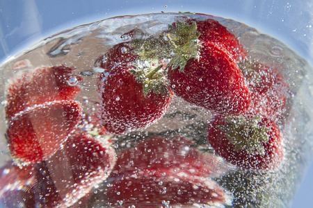 red ripe strwberries in crystal clear fresh water with sunlightの写真素材