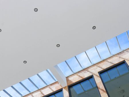 Modern business building interior with ceiling and lamps, architectural backgroundの写真素材