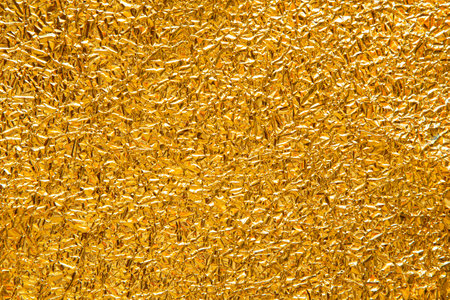 Festive background with crumpled golden foil close up textureの写真素材