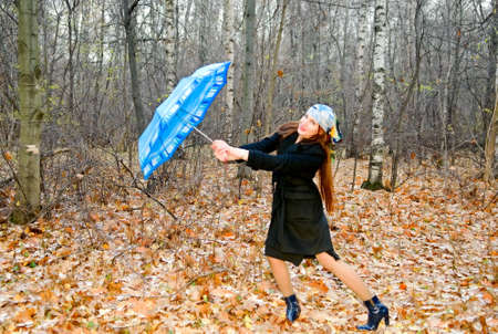 young woman with umbrella in autumn forestの写真素材