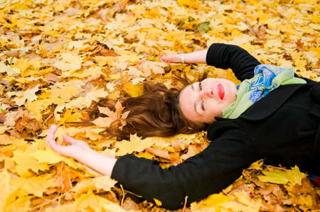 Young woman resting on autumn leavesの写真素材