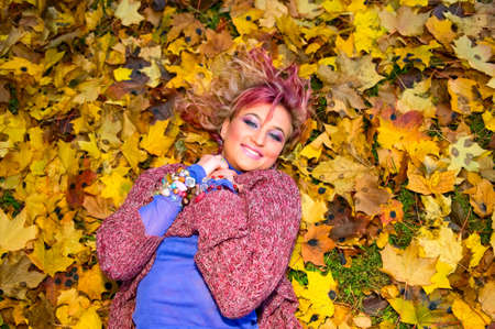 young smiling woman on autumn leaves