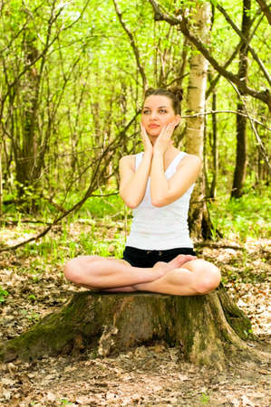 pretty young woman doing yoga in wild forestの写真素材