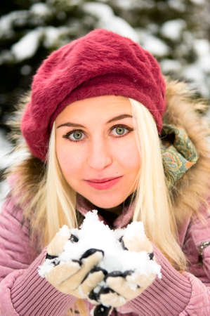 blonde young woman with snow in handsの写真素材