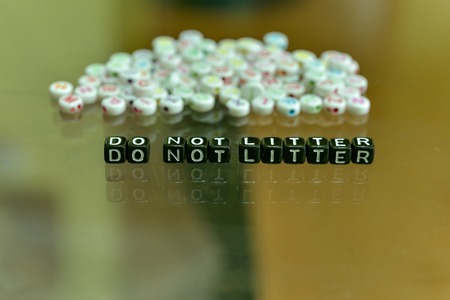 DO NOT LITTER  written with Acrylic Black cube with white Alphabet Beads on the Glass Backgroundの写真素材