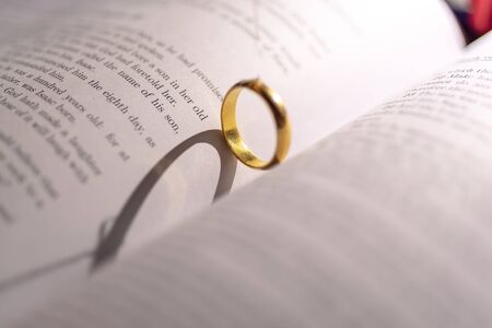 A wedding Ring on the bible with shadow of heart shape on the page