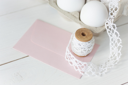 Easter eggs on wooden background with pink envelopeの写真素材