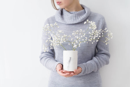 Young pretty women in grey dress holding flowers in concrete vazeの写真素材