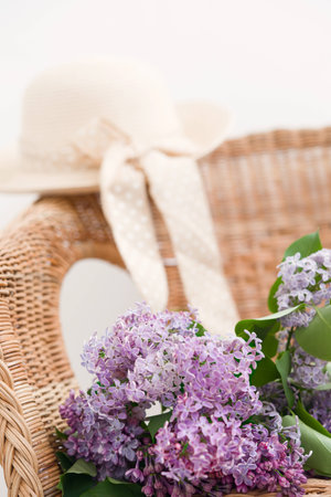 Lilac spring bouquet and straw hat on natural wooden chairの写真素材