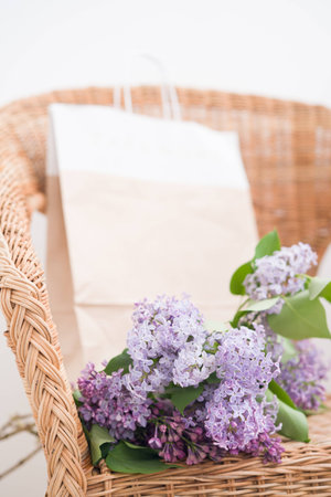 Lilac spring bouquet and craft bag on natural wooden chairの写真素材