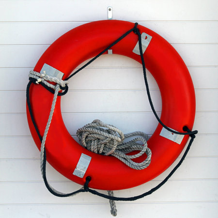 Photo of an orange life preserver with rope on a white board background