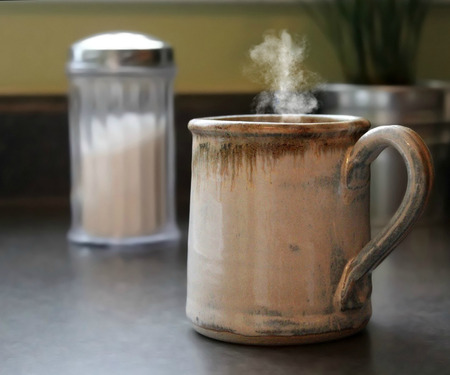 Photo of a cup of hot coffee with steam coming out of the cup, sitting on a counter topの写真素材