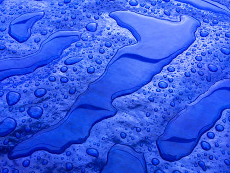 Droplets of rainwater on the blue tarpの写真素材