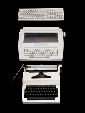 Two  white typewriters of different generations and computer keyboard in a line on a black background.の写真素材