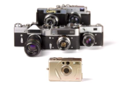 Compact digital photo camera on background of five defocused 35mm classic photo cameras