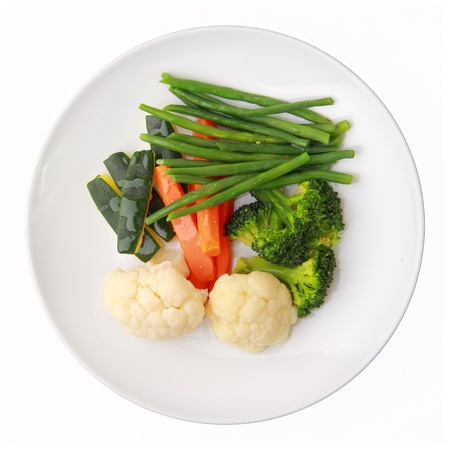 steamed vegetables of yellow, green and orange colors on white round dish isolated over white background. top view.の写真素材