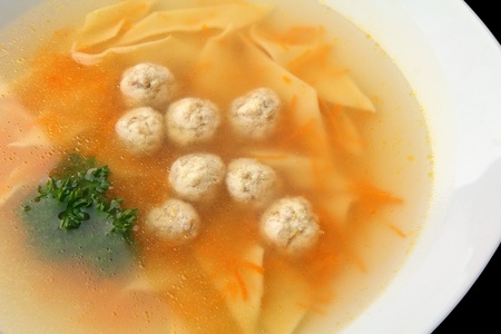 chiken noodle soup with noisettes in a white bowl closeup on a white backgroundの写真素材