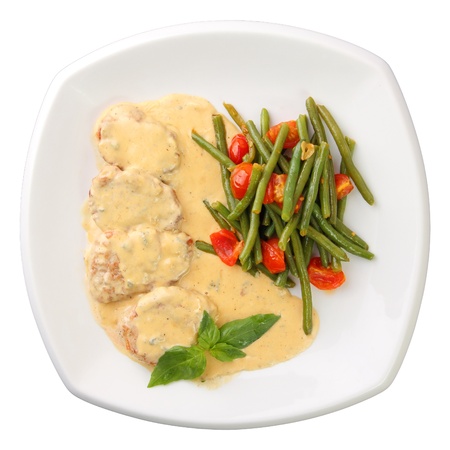 Medallions of veal in a creamy sauce with mushrooms and marinated vegetables on a white background. Top view.の写真素材