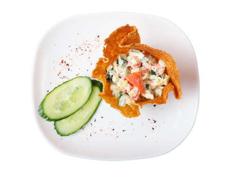 One basket made of cheese with salad with salmon and two pieces of cucumber on a white plate on white background, top viewの写真素材