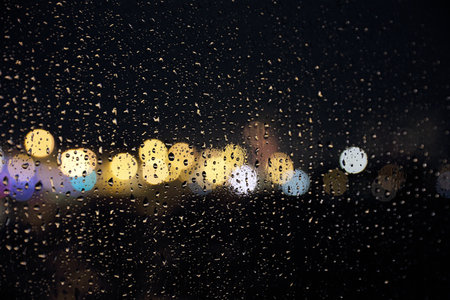Texture of raindrops on window glass with defocused lights on the backgroundの写真素材