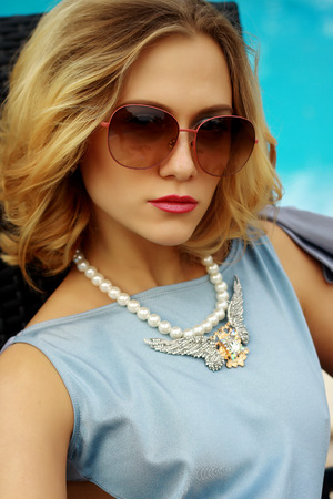 Young beautiful sexy blond girl in a bathing suit with glasses and ornaments around pool close-up portraitの写真素材