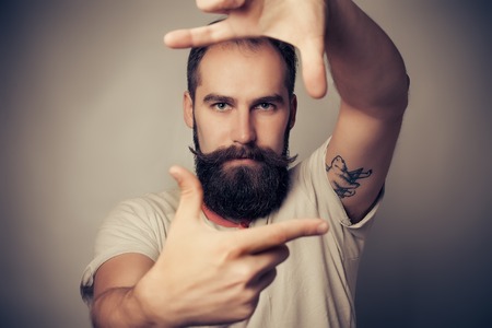 Young cheerful photographer with beard, while working in studioの写真素材