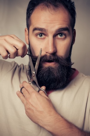 Man Cutting Beard against a grey backgroundの写真素材