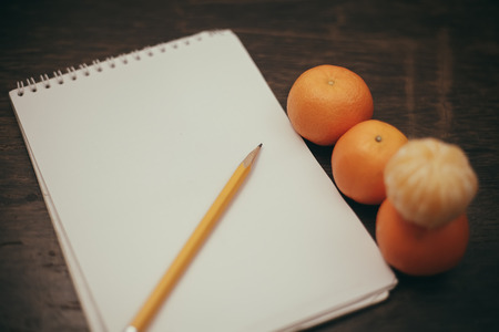 Tangerines notebook pencil coffee on old wooden backgroundの写真素材