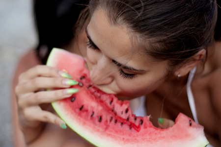 Cropped image of a young woman eating fresh watermelon on the foregroundの写真素材