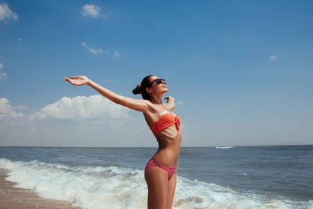 Beautiful young girl flying with seagulls on the sea, the girl in sunglasses and a swimsuit. He smiles and enjoys sea and sunの写真素材