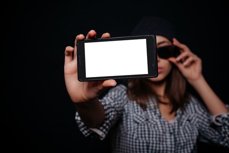 Hipster cool girl taking picture on smartphone self-portrait, screen view, snapshot studio on a black background, Phone white screenの写真素材