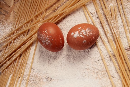 white flour and eggs, and pasta on a wooden background , view from aboveの写真素材