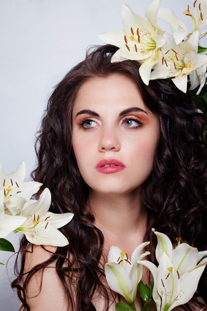 beauty, people and health concept - beautiful young woman with white flowers and bare shoulders over white backgroundの写真素材