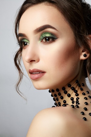 Elegant young lady with evening smart make up and beads on her neck. Make-up of woman eye with khaki eyeshadow. Beauty portrait of a girl model with make-up,green eyes. Creative Professional makeup.の写真素材