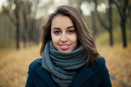 Autumn fashion girl wearing trench coat in sun flare foliage. Fall woman portrait of happy lovely and beautiful mixed race Caucasian young woman in forest in fall colors.の写真素材